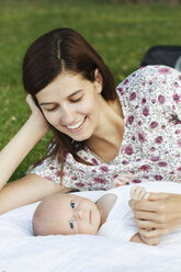 Nahaufnahme einer Mutter mit Baby auf einer Wiese im Park - CAVF12288