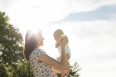 Seitenansicht einer lächelnden Mutter mit Baby gegen den Himmel an einem sonnigen Tag - CAVF12290