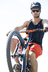 Man performing stunt with bicycle against clear sky on sunny day - CAVF12303