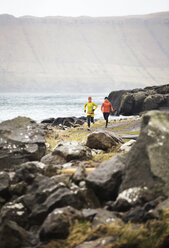 Friends jogging on footpath by coastline - CAVF12352