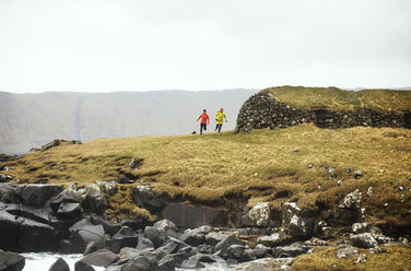 Freunde joggen auf einem Feld vor der felsigen Küste - CAVF12353