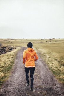 Rückansicht einer Frau, die auf einem Feldweg joggt - CAVF12360