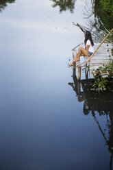 High angle view of thoughtful woman sitting on pier by river - CAVF12364