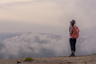 Seitenansicht einer Wanderin mit Rucksack, die bei nebligem Wetter auf einem Berg steht - CAVF12390