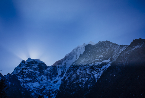 Niedriger Blickwinkel auf schneebedeckte Berge gegen blauen Himmel in der Abenddämmerung, lizenzfreies Stockfoto