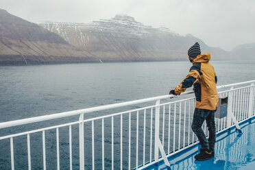 Side view of man standing by railing on boat during rainy season - CAVF12421