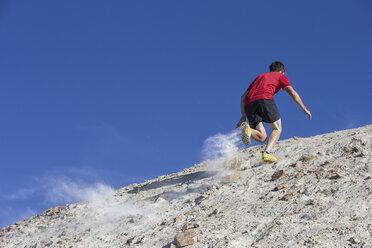 Niedriger Blickwinkel von Mann joggen auf Berg gegen klaren blauen Himmel - CAVF12441