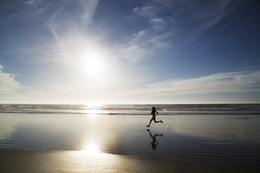 Silhouette einer Frau beim Joggen am Meeresufer gegen den Himmel an einem sonnigen Tag - CAVF12443