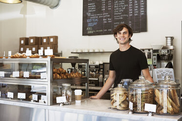 Portrait of happy man standing at store counter - CAVF12474