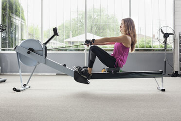 Frau trainiert auf einem Rudergerät im Fitnessstudio - CAVF12488