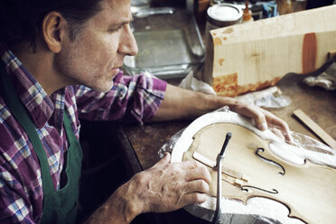 High angle view of man making violin in workshop - CAVF12510