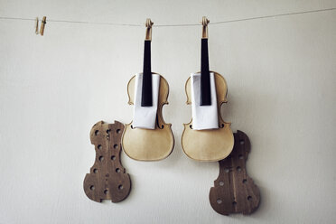 Incomplete violins hanging on string against wall - CAVF12524