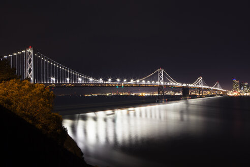 Beleuchtete Oakland Bay Bridge über dem Meer gegen den Himmel bei Nacht - CAVF12560