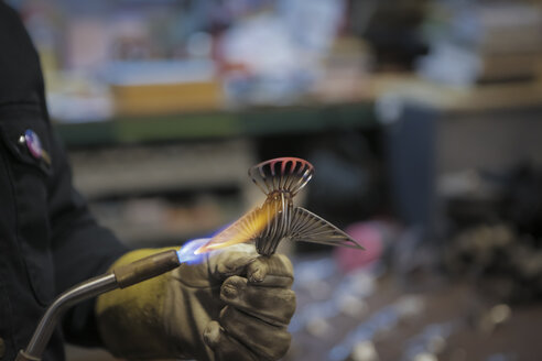 Abgeschnittene Hand eines Ingenieurs, der in einer Fabrik mit einem Propangasbrenner lötet - CAVF12569