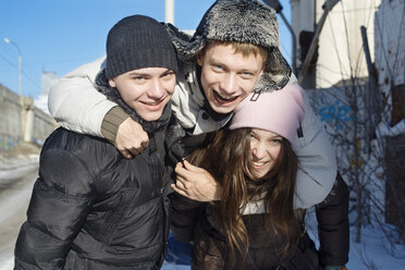 Portrait of cheerful man embracing friends on sunny day - CAVF12771