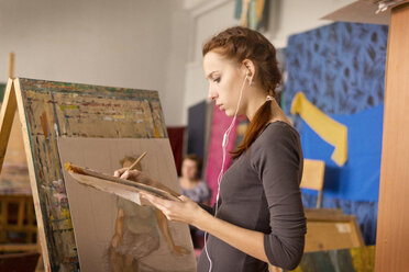 Junge Frau malt im Stehen im Kunstunterricht - CAVF12780
