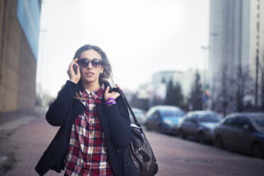 Junge Frau mit Sonnenbrille und Umhängetasche in der Stadt - CAVF12787