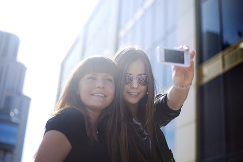 Niedriger Winkel Blick auf glückliche Frau, die Selfie mit Freund in der Stadt, lizenzfreies Stockfoto