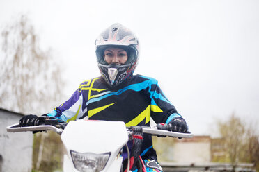 Porträt einer Frau beim Motorradfahren gegen den Himmel - CAVF12807