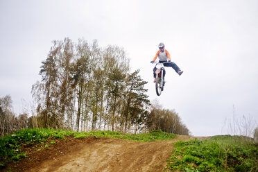 Low angle view of man jumping with dirt bike while racing - CAVF12809