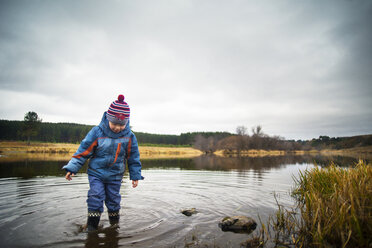 Boy standing on river against cloudy sky - CAVF12847