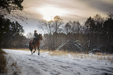 Woman riding horse on snow covered road against sky - CAVF12854