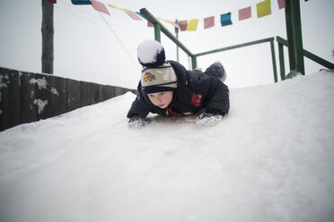 Boy sledding on snow covered hill - CAVF12862