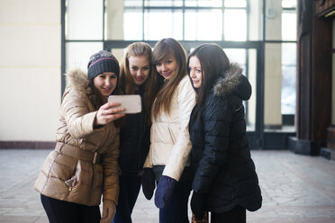 Weibliche Freunde, die ein Selfie mit ihrem Smartphone machen, während sie vor einem Gebäude stehen - CAVF12864