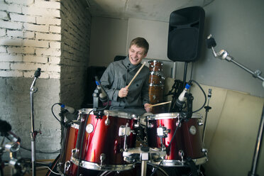 Happy man playing drum kit at home - CAVF12868