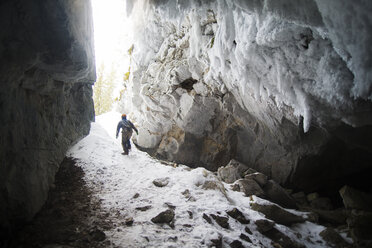 Rückansicht einer Frau, die im Winter inmitten von Felsformationen spazieren geht - CAVF12883