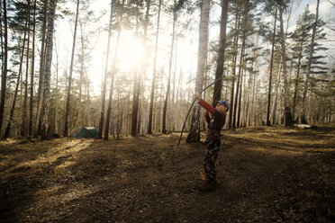 Junge, der im Wald stehend auf ein Ziel zielt - CAVF12904