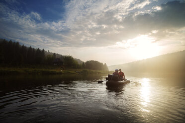 Mann und Frau beim River Rafting bei Sonnenuntergang - CAVF12944