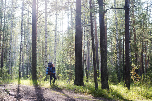 Männlicher Wanderer mit Rucksack, der durch Bäume im Wald läuft - CAVF12962