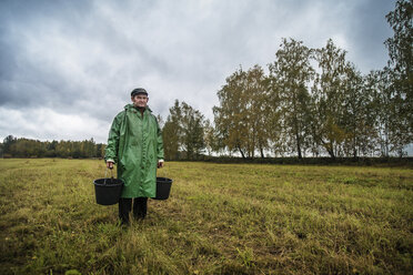 Porträt eines männlichen Landarbeiters auf einem Feld vor bewölktem Himmel - CAVF12971