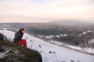 Frau sitzend auf Berg gegen Himmel im Winter - CAVF13008