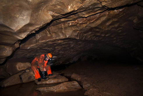 Handwerker, der in einer Höhle sitzend einen Stiefel reinigt - CAVF13024