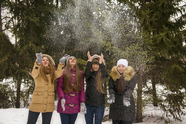 Happy female friends playing with snow in forest - CAVF13026