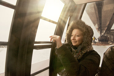 Nachdenkliche Frau schaut durch das Fenster der Seilbahn - CAVF13028