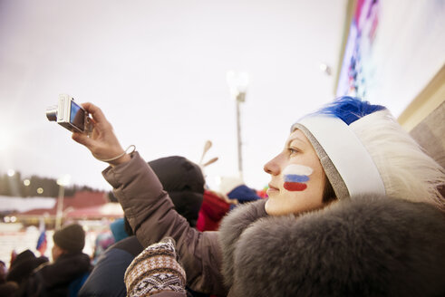 Russischer weiblicher Fan fotografiert Fußballfeld durch Kamera gegen klaren Himmel - CAVF13029