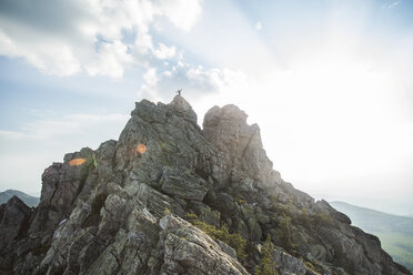 Distant view of hiker standing on mountain against cloudy sky - CAVF13037