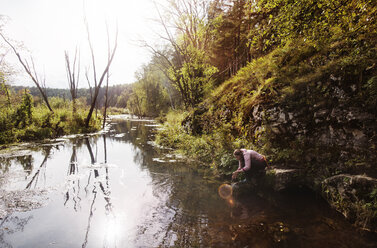 Seitenansicht einer Frau beim Händewaschen am Fluss - CAVF13051