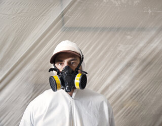 Porträt eines Malers mit Gasmaske vor Plastik in einer Werkstatt - CAVF13098