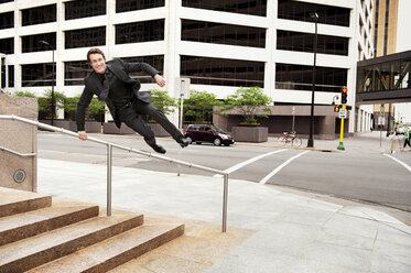 Businessman jumping over railing at sidewalk in city - CAVF13125