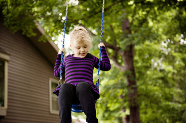 Girl enjoying on swing against trees at park - CAVF13131