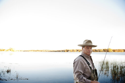 Portrait of confident man standing at lake against clear sky - CAVF13159