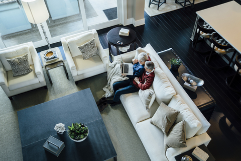 High angle view of senior couple using laptop computer while sitting on sofa in living room stock photo