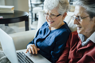 Älteres Paar benutzt Laptop im Wohnzimmer - CAVF13231