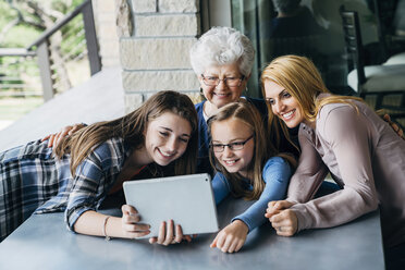 Schwestern nehmen Selfie mit Mutter und Großmutter durch Tablet-Computer auf Veranda - CAVF13258