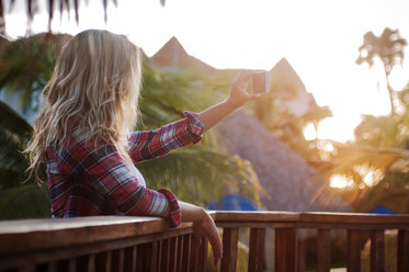 Seitenansicht einer Frau, die ein Selfie macht, während sie an einem sonnigen Tag am Geländer steht - CAVF13267