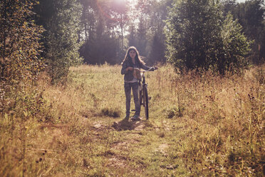 Mädchen mit Fahrrad auf einem Feld - CAVF13293